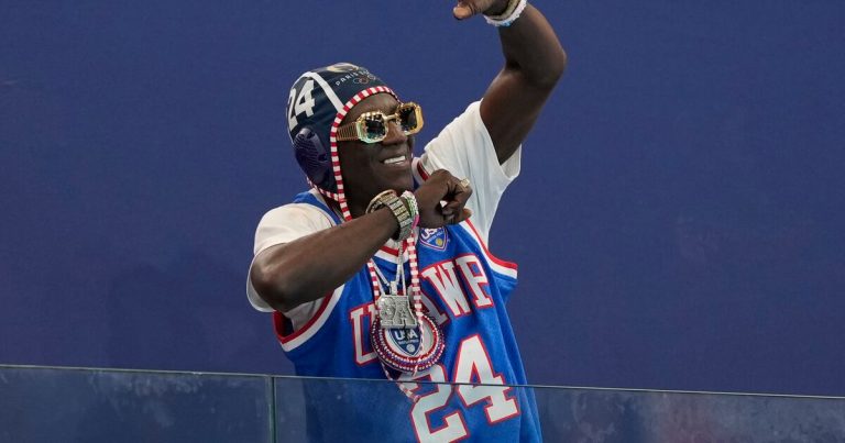 Flavor Flav ayuda a la lanzadora olímpica de disco Veronica Fraley