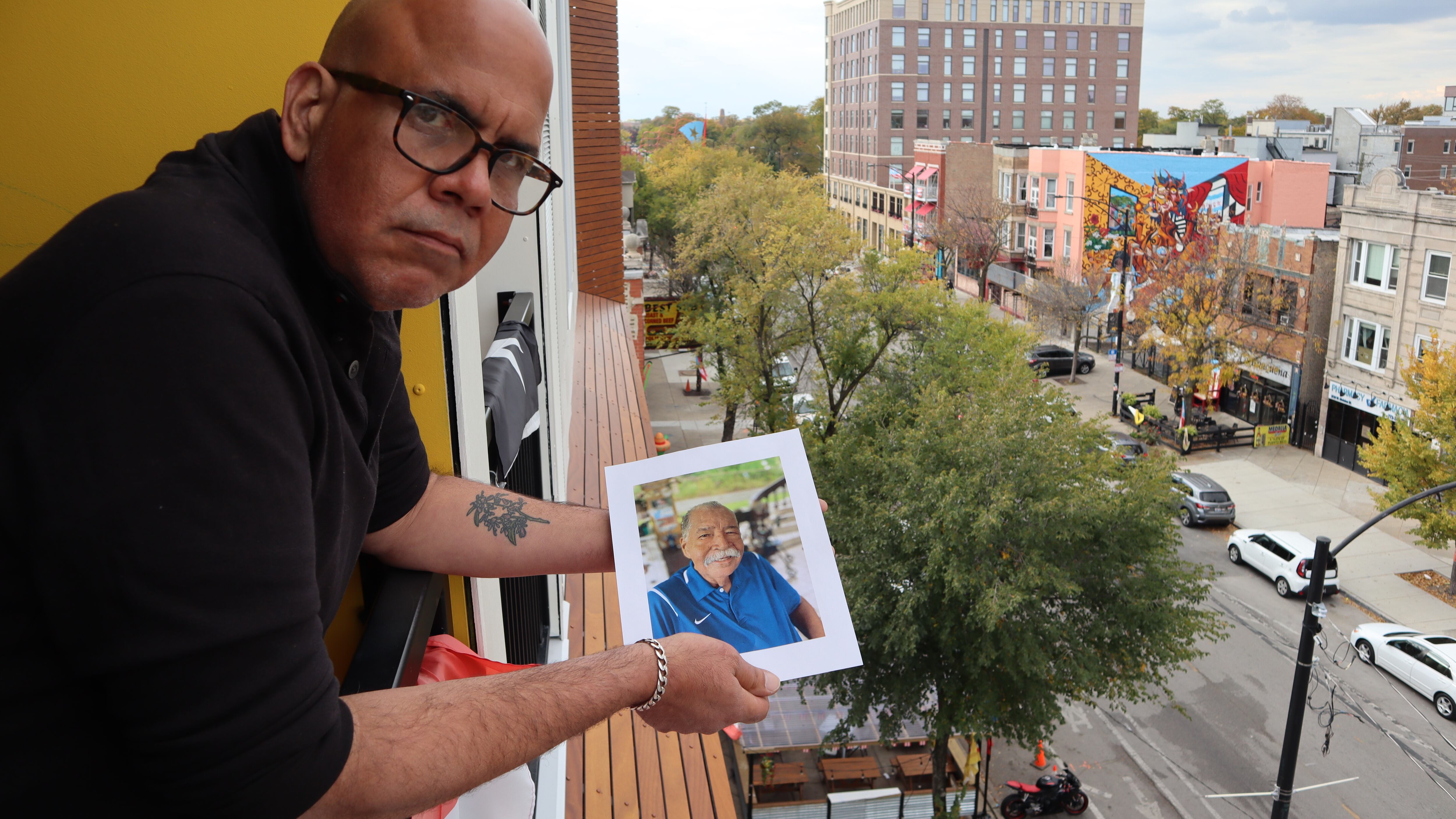 Elías Carmona Rivera sostiene la foto de su padre, Elías Carmona Alejandro, en el balcón de su apartamento en el barrio puertorriqueño de Chicago. Elías y su hermana Sandra son un ejemplo de los retos que enfrentan muchos hijos a cargo de cuidar a sus padres envejecidos, tanto en Puerto Rico como desde la diáspora.