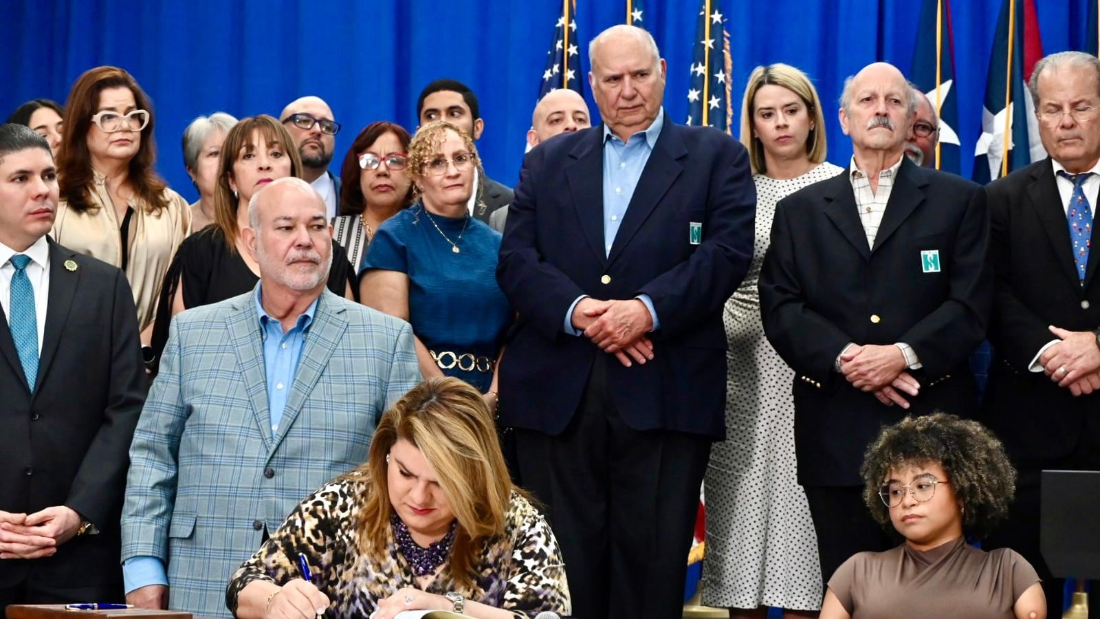 Gobernadora firma ley rodeada de legisladores y colaboradores de SER de Puerto Rico.